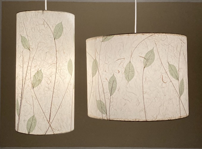 set of two lit drum pendants of different shapes and sizes showing light green leaves