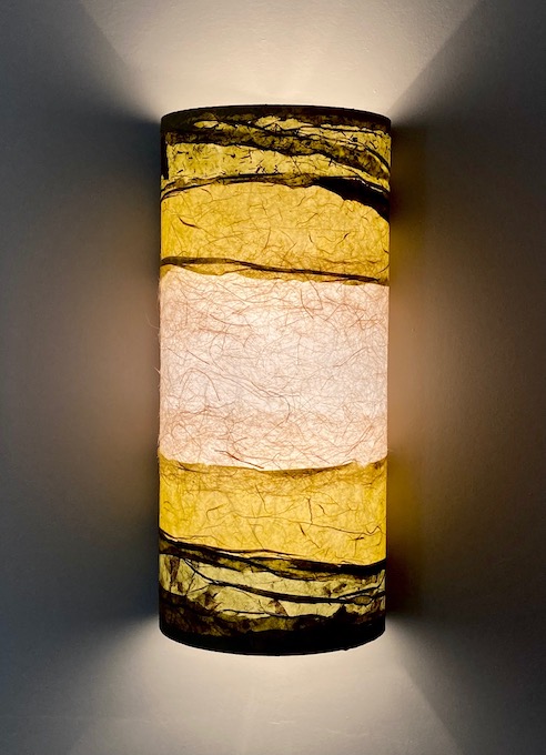 one lit layered sconce with woven papers in tones of gold and brown