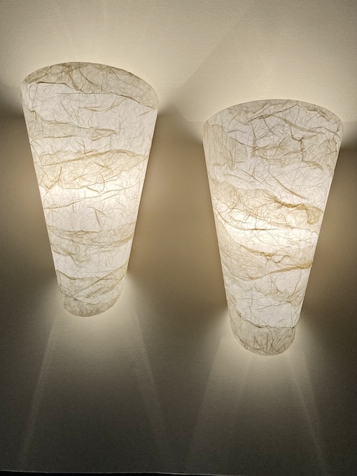 Set of two lit conical sconces in neutral paper and cone pointed up