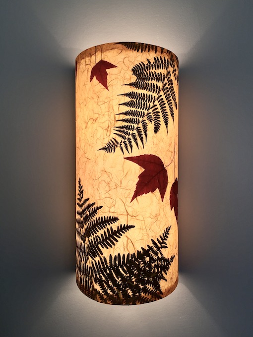one lit sconce with fern and maple leaves golden color