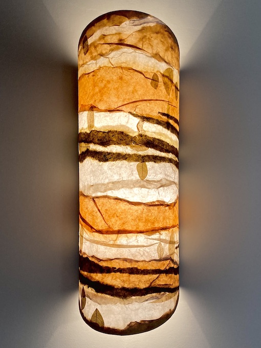 one lit sconce with bands of orange and brown and leaves